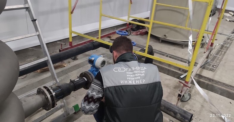 Специалист в жилете ГАЗ-ВОДА монтирует соединительный узел на трубопроводе крупным планом